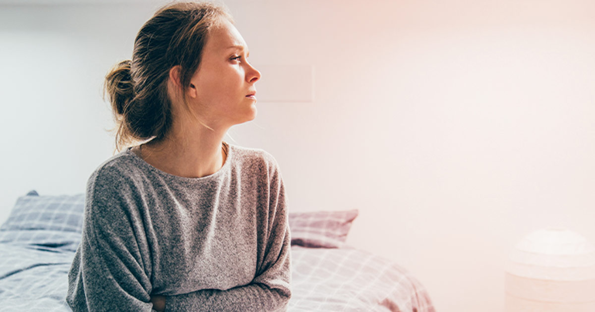 crying woman sitting on bed - Seasonal Affective Disorder (SAD)