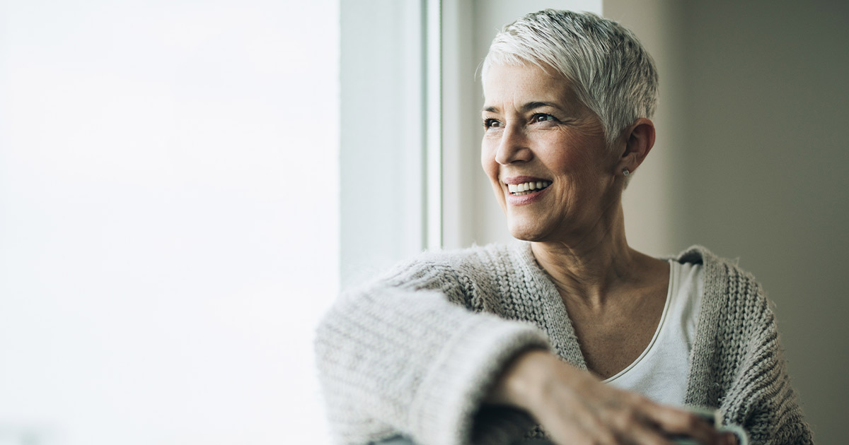 older woman gazing out of a sunny window - Menopausal Transition and Cardiovascular Disease - Axia Women's Health