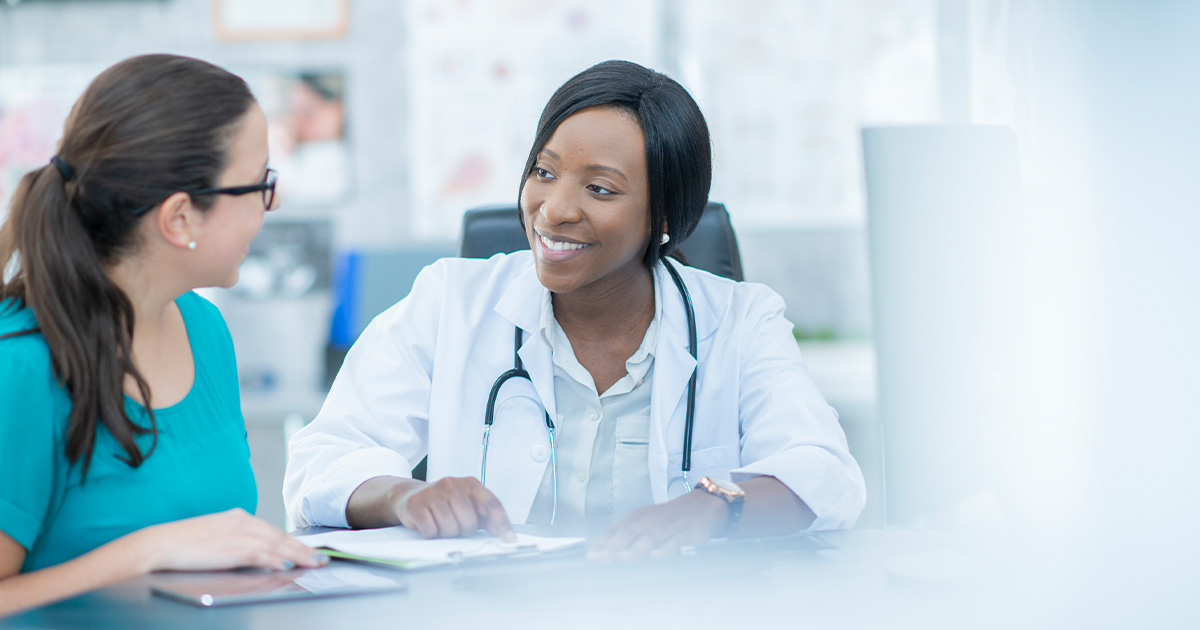 young woman speaking with doctor in clinical setting - Fibroids