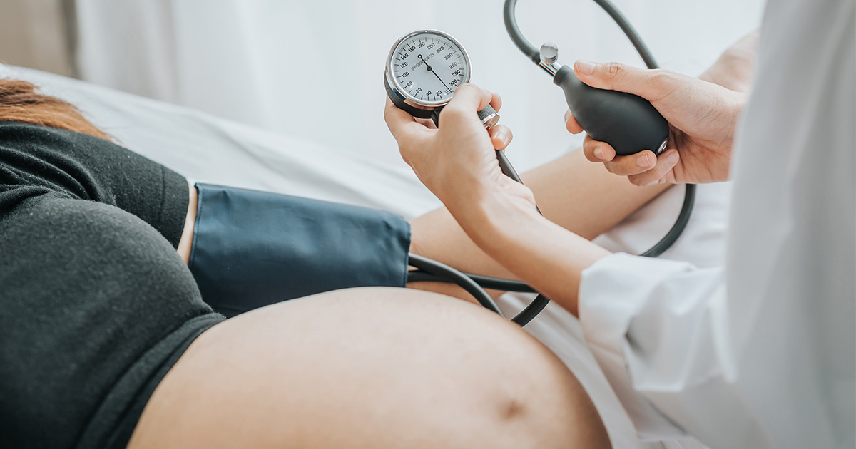 pregnant woman lying in bed & doctor holding stethoscope near stomach - High risk pregnancy