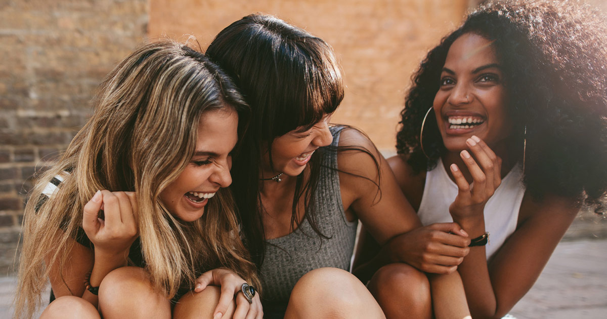 three young women sitting and laughing together - Family Planning
